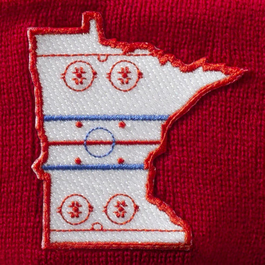 Details of red & royal pom hat with patch in the shape of the state outline of Minnesota with the details of a hockey rink on the inside of the state outline. minnesota clothing, minnesota apparel, minnesota accessories, minnesota gifts, minnesota goods, minnesota-themed clothing, minnesota-themed apparel, minnesota-themed gifts, minnesota-themed goods, minnesota pom hats, minnesota pom pom hats