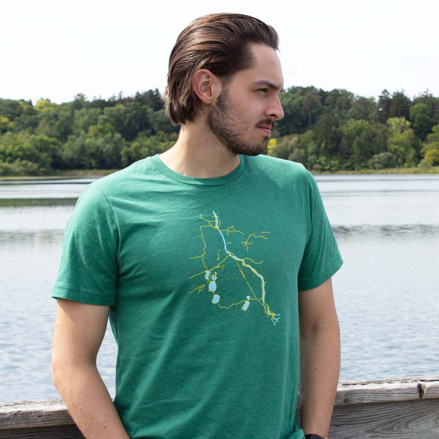 Photo of man wearing green t-shirt with Minneapolis bike trails in yellow and lakes & rivers in blue, bike trails, biking, minnesota, twin cities, minneapolis, st paul, minnesota-themed clothing, clothing, apparel, accessories, gifts, goods, t-shirt, t shirt, tee, t-shirts, t shirts, tees